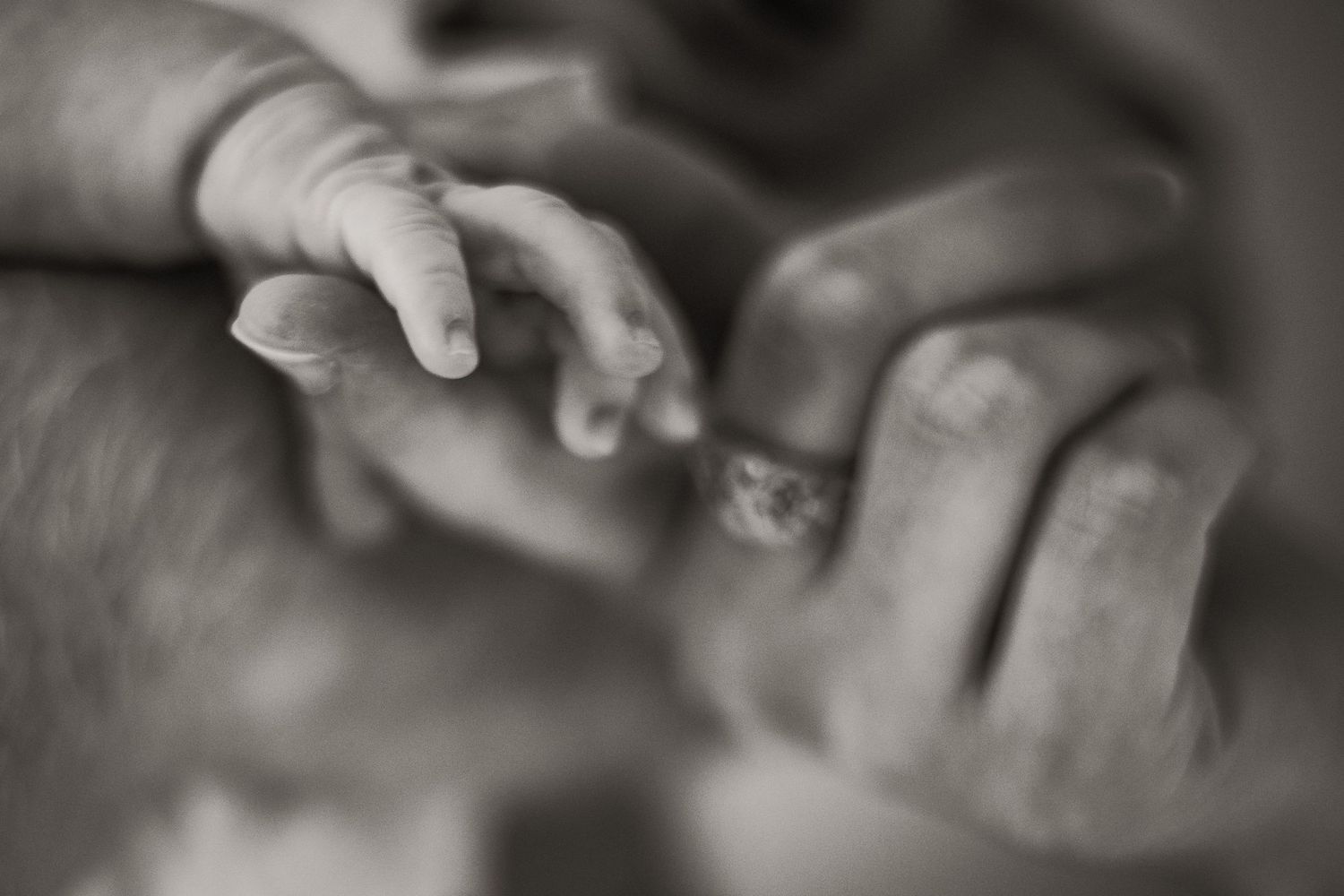 A tender black and white close-up photograph of two hands gently touching and connecting.