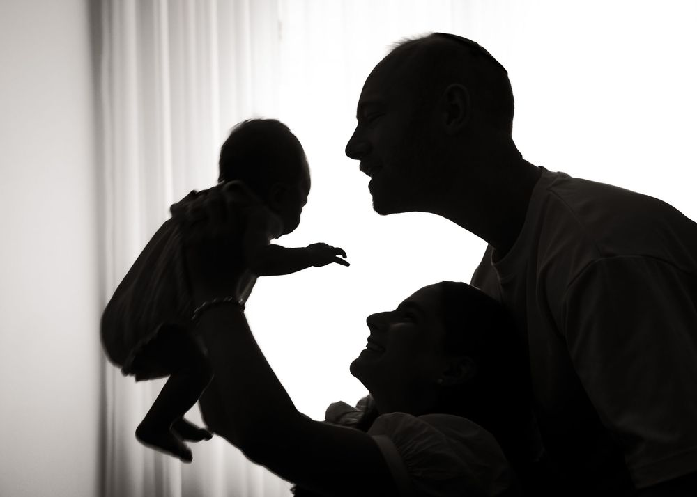 Silhouetted figures in profile against a light background create a dramatic black and white composition.