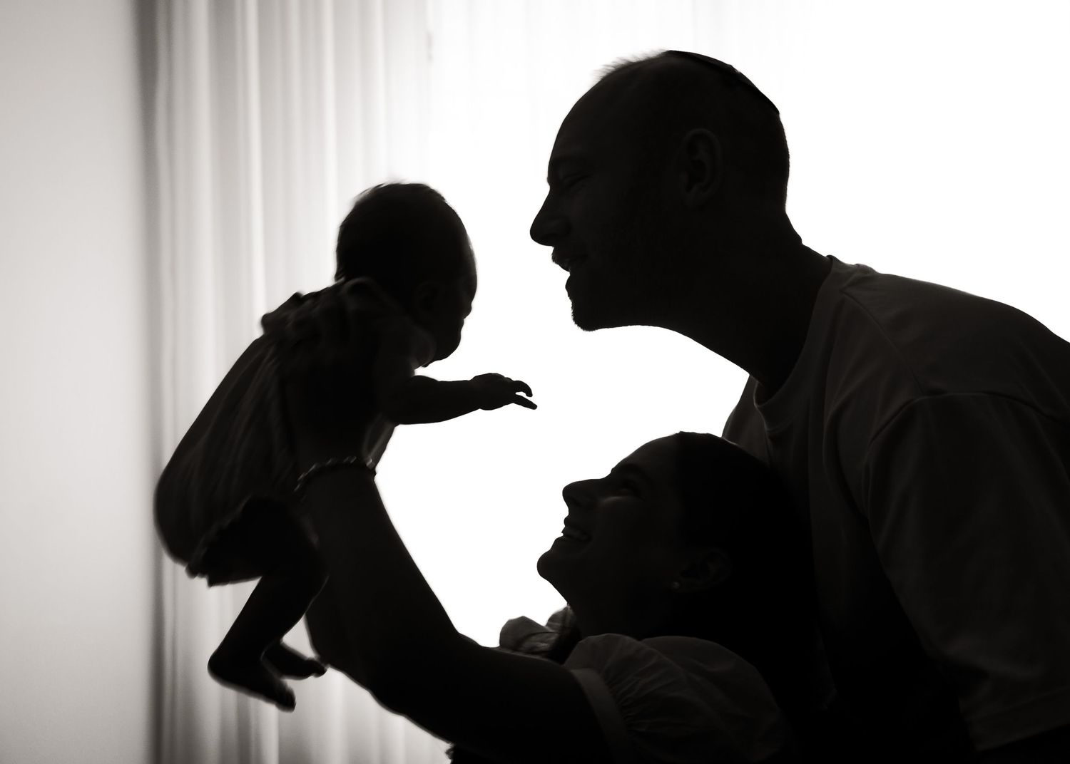 Silhouetted figures in profile against a light background create a dramatic black and white composition.