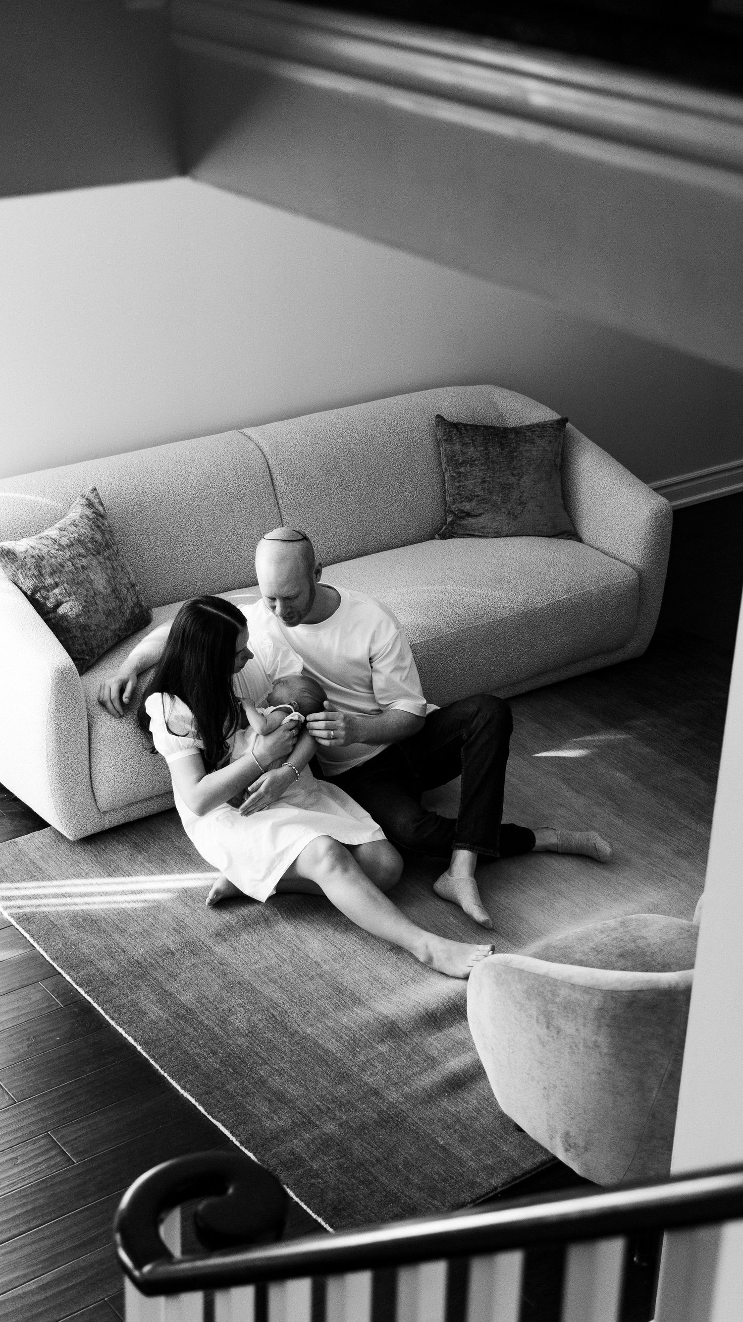 A person lying on a light-colored couch reading or using a device in a black and white photograph.