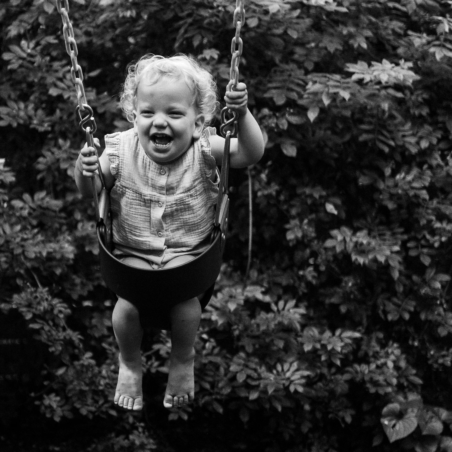 Black and white photo sequence of a child swinging and laughing.