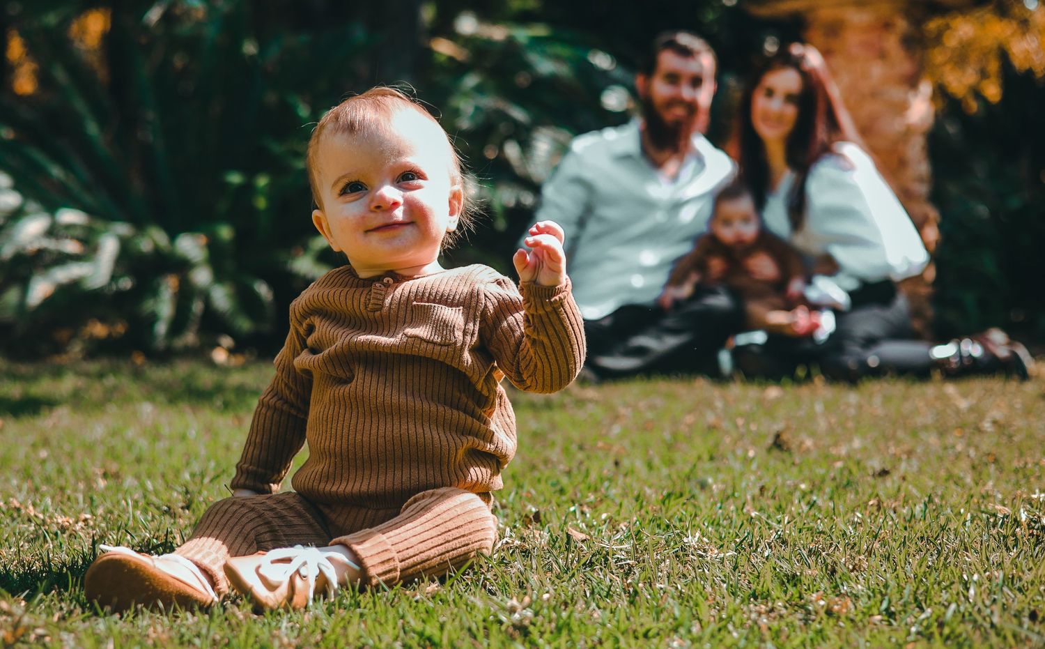 Children playing together on grass during a sunny outdoor gathering.