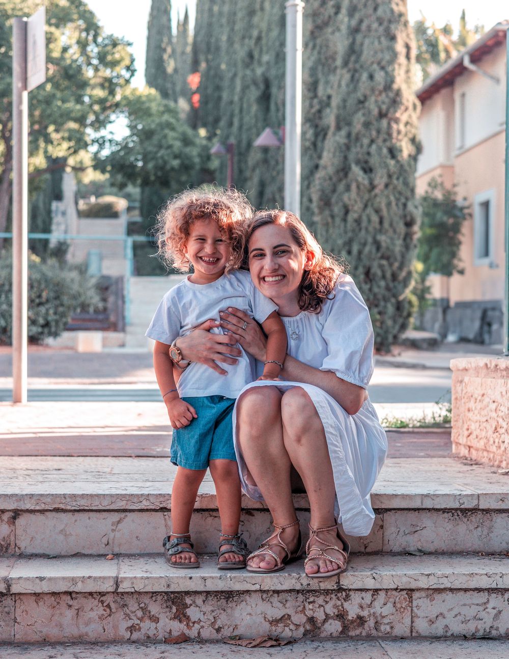 Parent and child sharing a joyful moment while sitting on stone steps outdoors.