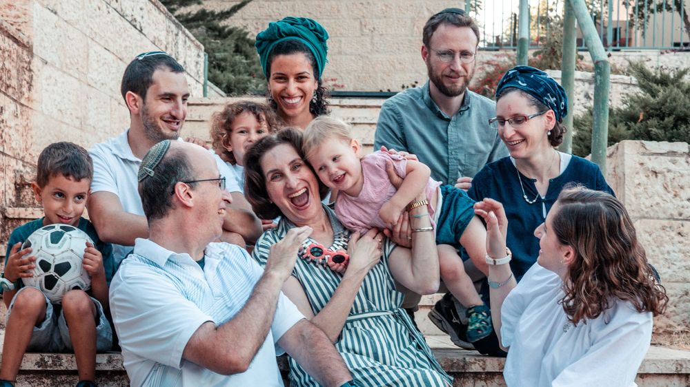 Group of friends and family laughing together while sitting on outdoor steps.