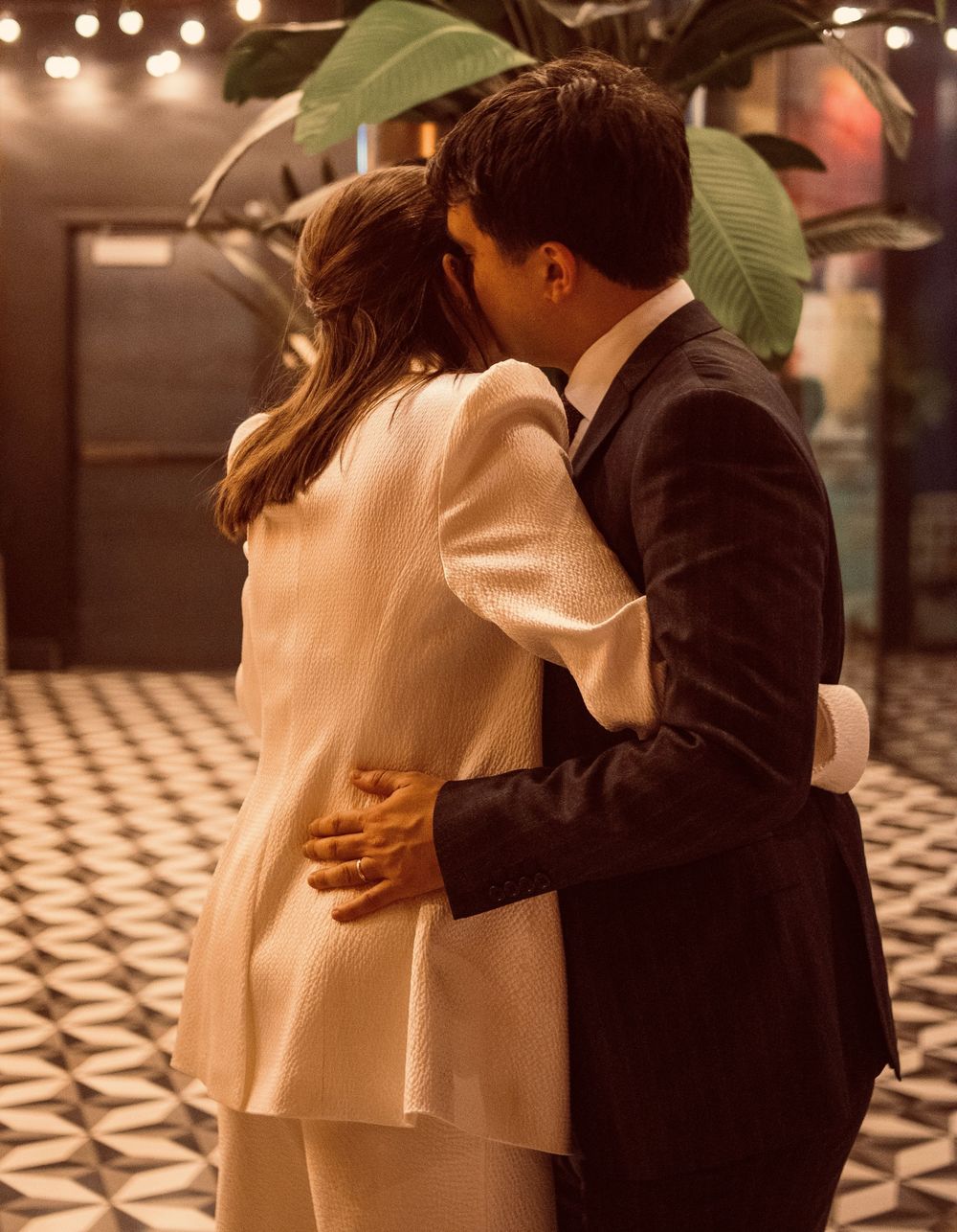 Newlyweds sharing romantic kiss in stylish venue with geometric tile floor and tropical plants.