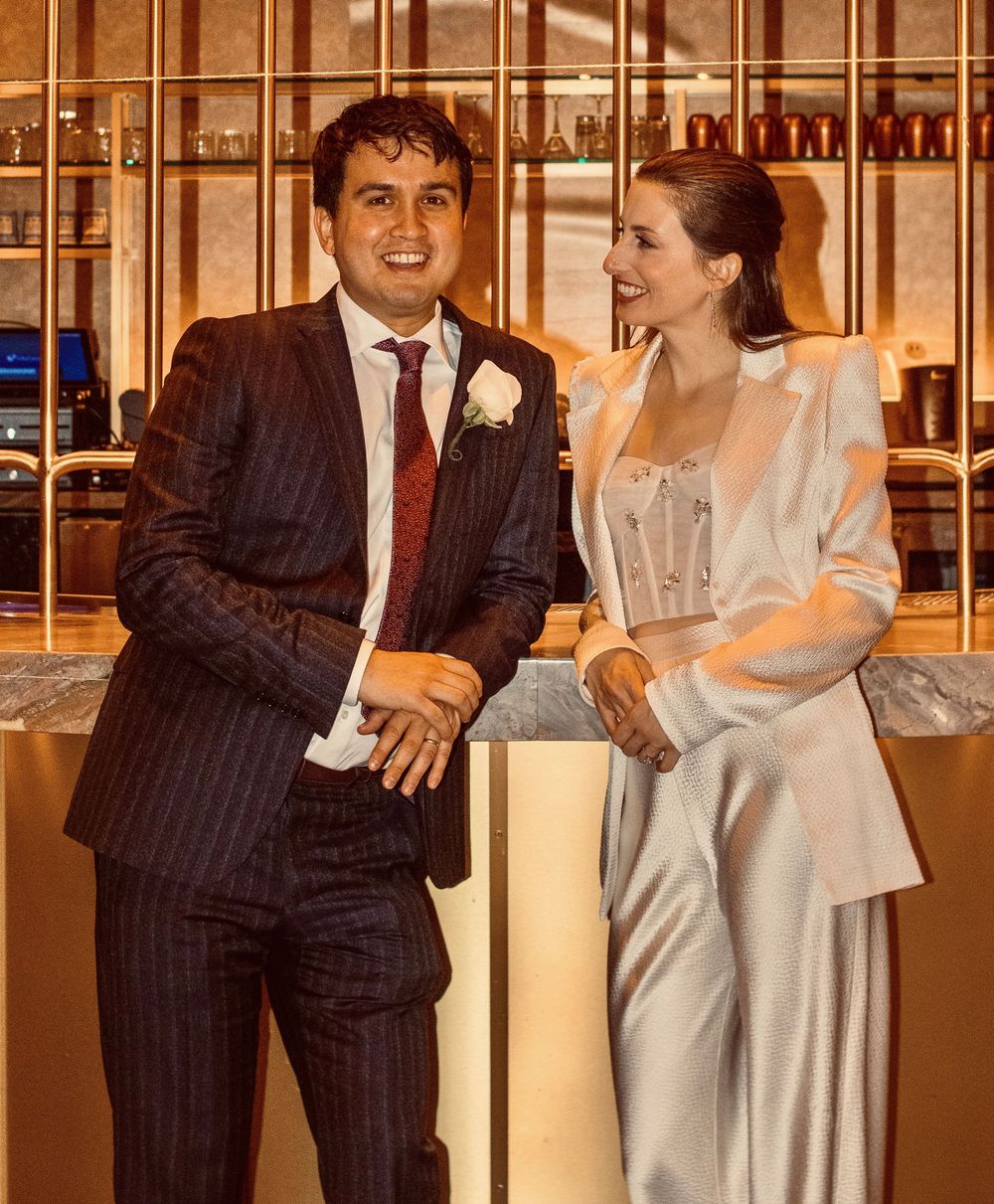 Happy couple in wedding attire laughing together at a stylish bar venue.