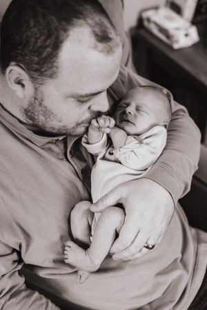 Series of gentle kisses and cuddles between parent and sleeping infant in muted tones.