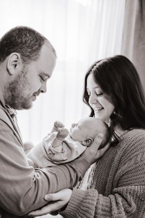 A tender black and white photo series showing intimate moments between parents and their newborn baby.