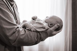 Gentle close-up shots of parents cradling and bonding with their newborn in a bright room.