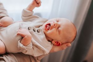 Close-up profile views of a sleeping newborn baby in white clothing against a light background.