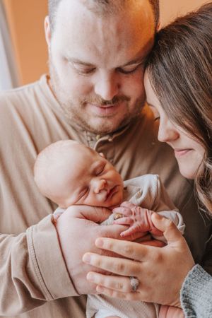 Warm-toned intimate family photos showing parents bonding with their sleeping newborn.