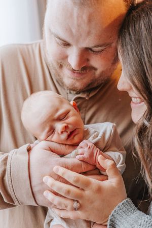 Sequence of loving family moments as parents embrace their newborn in warm lighting.