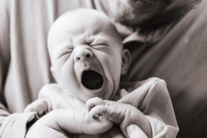 Black and white series showing emotional moments between parents and crying newborn.