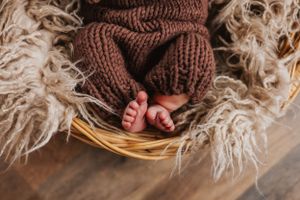 Newborn baby details photographed with brown knit blanket and wicker basket textures.