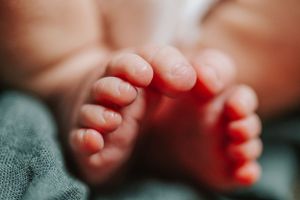 Close-up of tiny newborn baby feet against green fabric background.