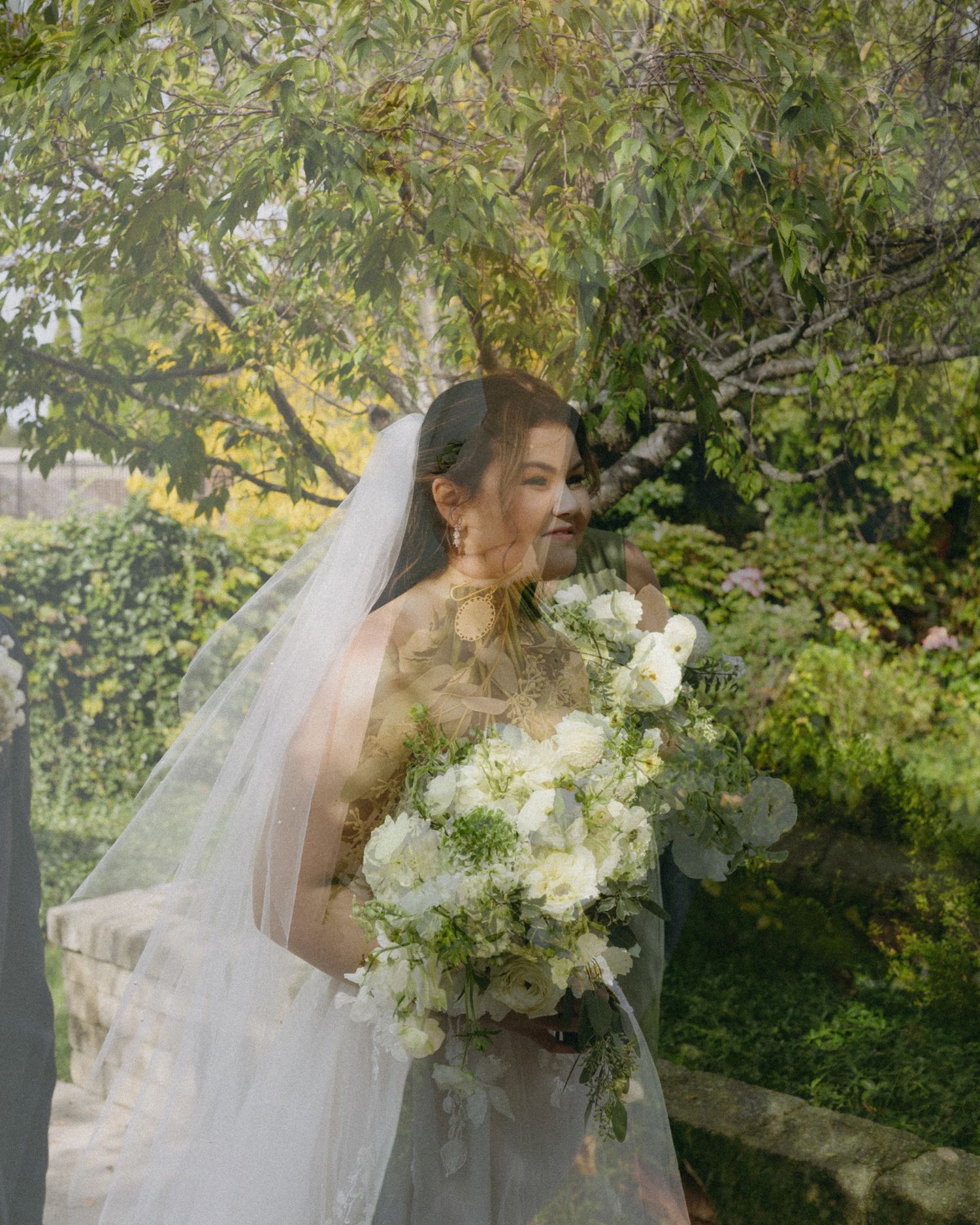A bride looks off camera and smiles at her groom after their wedding ceremony during their family and bridal portraits.