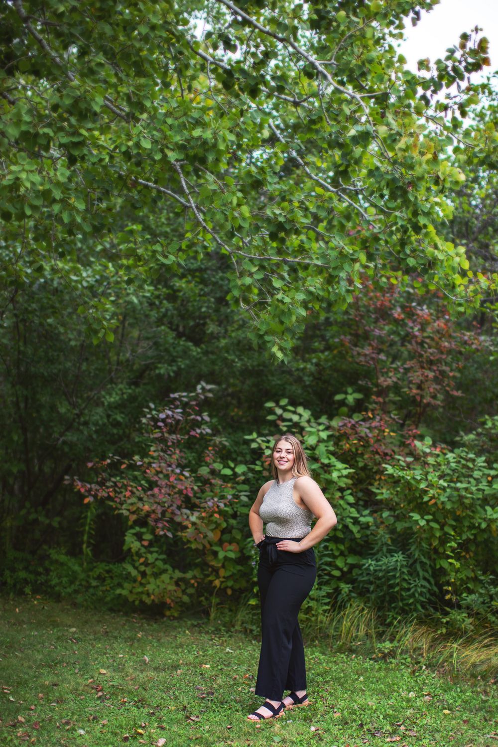 A series of outdoor photos showing someone in a black dress posing against lush green foliage and bushes in a garden setting.