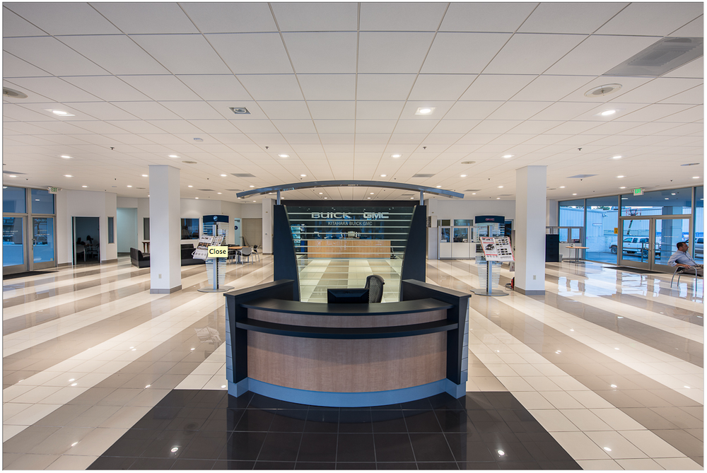 Empty retail space with curved reception counter, recessed lighting, and commercial storefront windows.