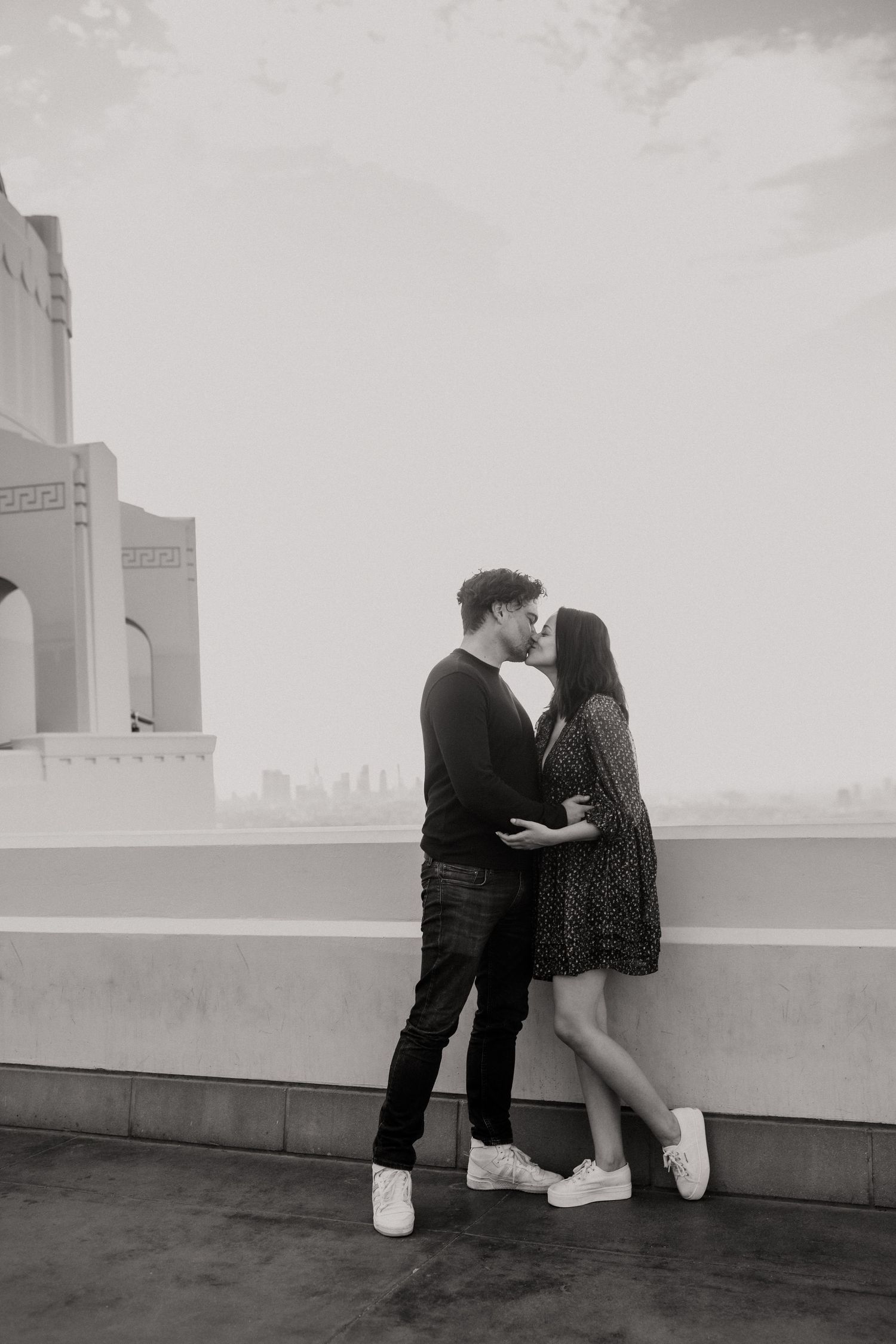 Black and white romantic portrait against architectural backdrop with city views.