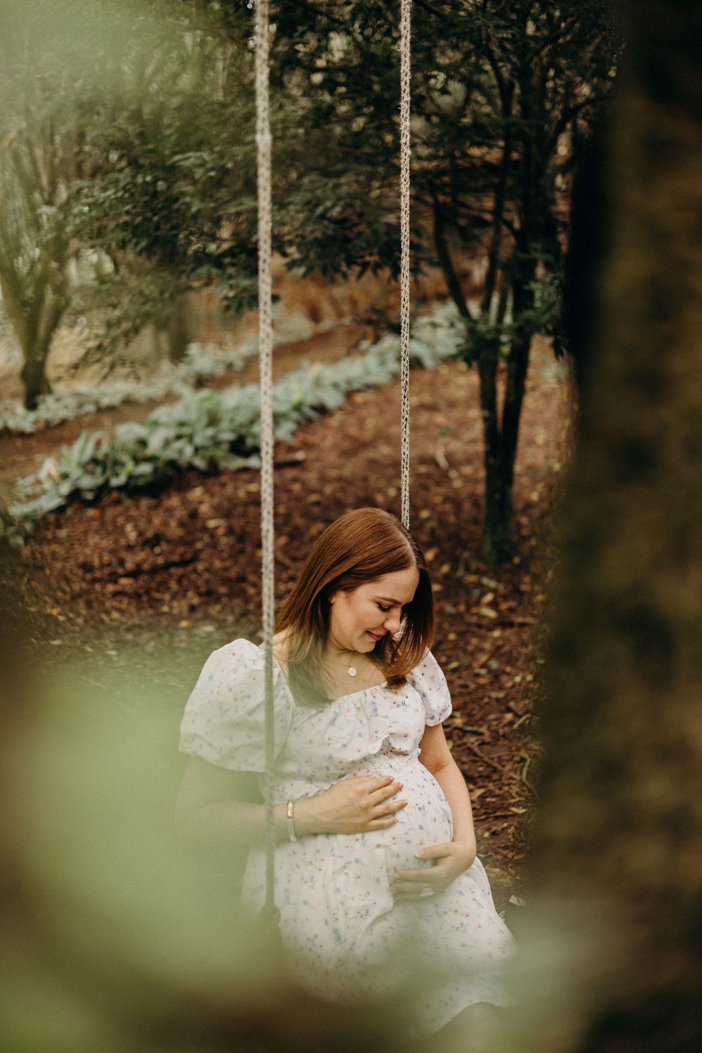 A dreamy forest scene with a white rope swing and soft natural lighting filtering through the trees.