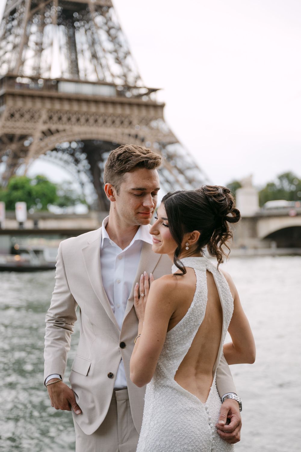 Romantic couple shares intimate moments by the Seine River with the Eiffel Tower in the background.