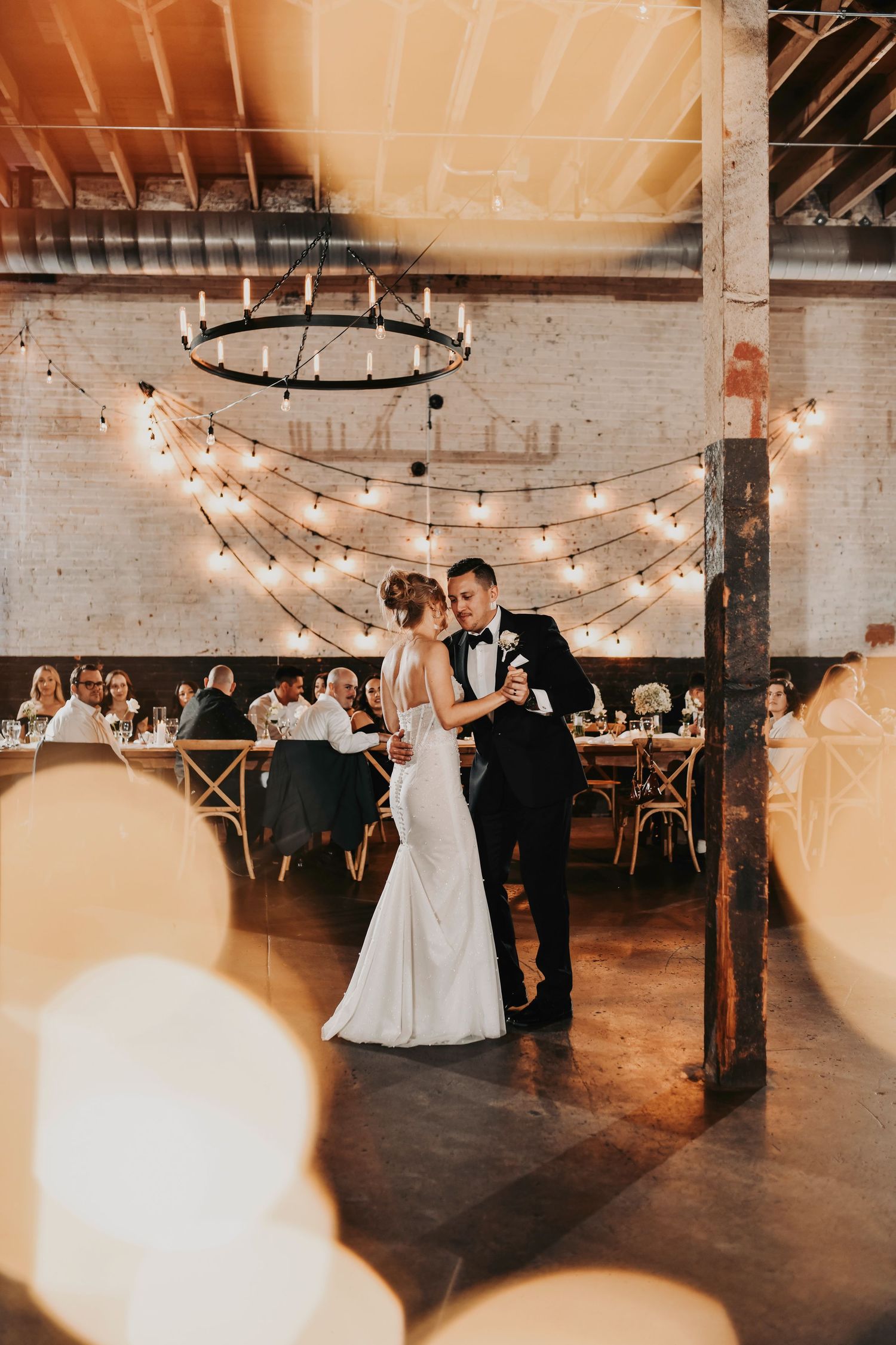 Candid wedding photo of couple slow dancing under soft reception lighting
