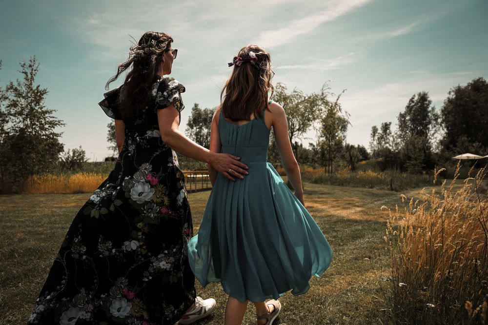 A couple in a grassy field at sunset share an intimate moment in vintage-style clothing and warm lighting.