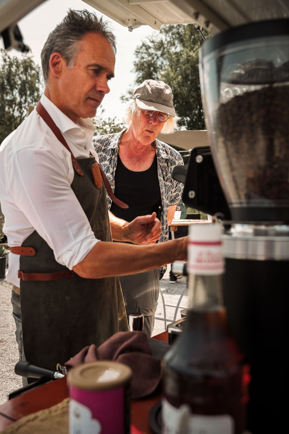 Bartenders preparing drinks at an outdoor beverage station during a sunny day.