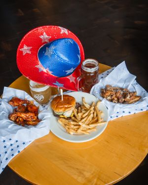 Red and blue plastic plates filled with fried foods and french fries on a wooden table surface.