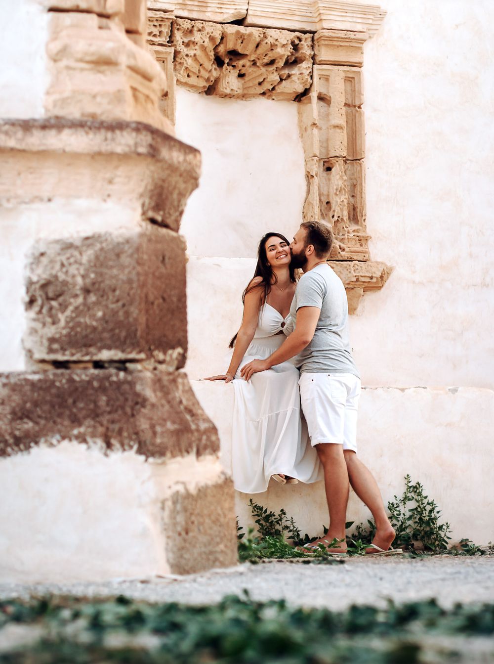 A romantic couple posing against the historic white stone walls of Betancuria village - Professional photoshoot in Fuerteventura