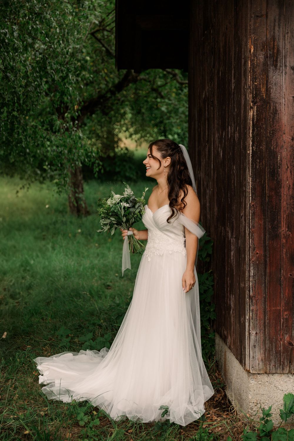 Romantic bridal portrait against rustic wooden backdrop in a natural outdoor setting.