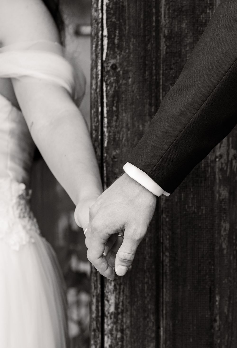 Close-up of hands clasped together against a rustic wooden background.