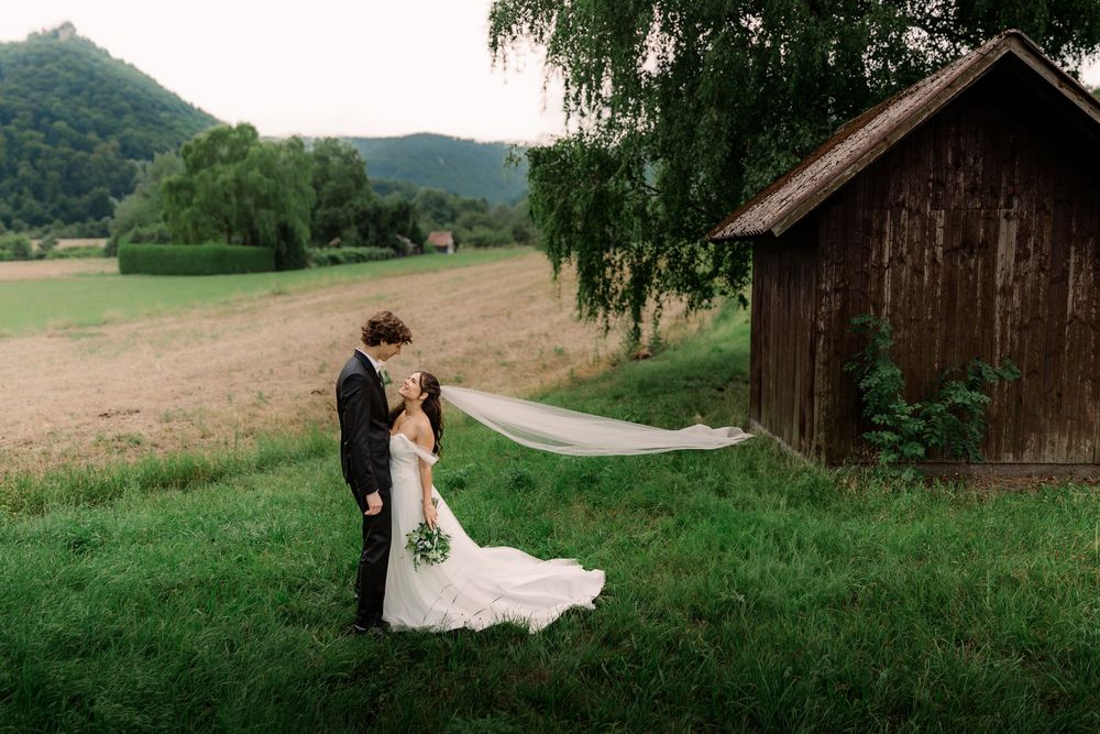 A scenic wedding photo with rolling hills and a rustic barn in the background.