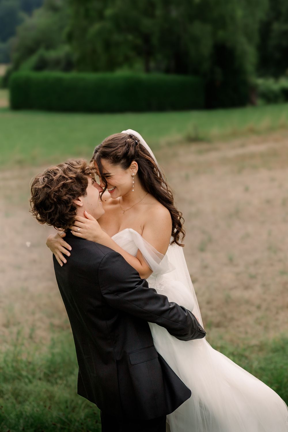 A romantic wedding couple sharing an intimate moment in a meadow.