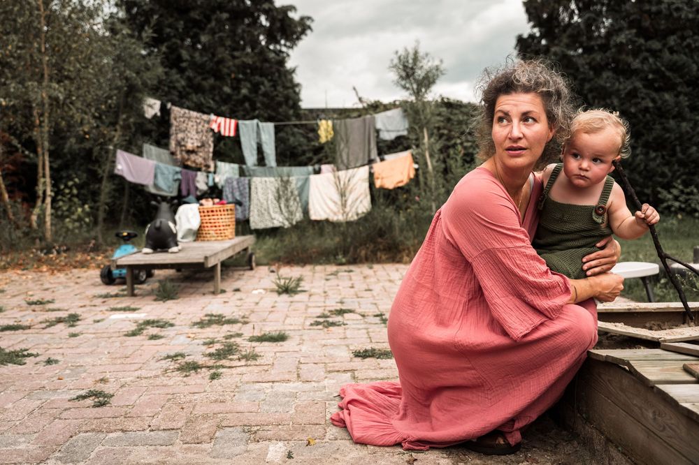 Person in coral dress sitting on steps with laundry hanging on clothesline in background.