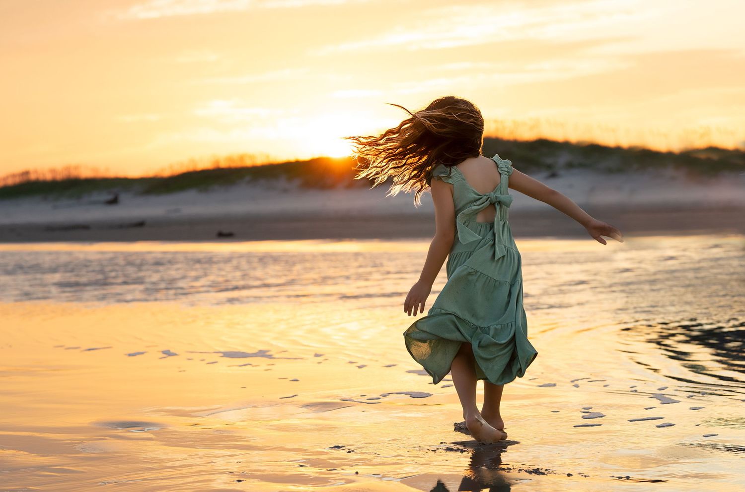 Child spinning along the shoreline at sunset in Matagorda Beach, Texas during a family beach session