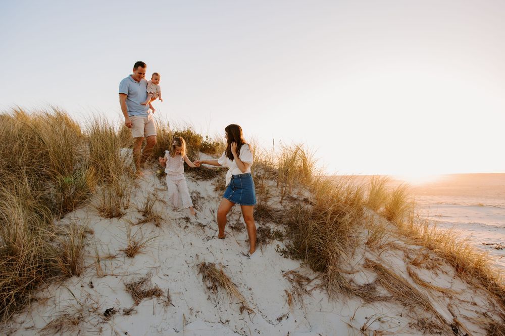 A group enjoying sunset together while standing on sandy dunes near the ocean.