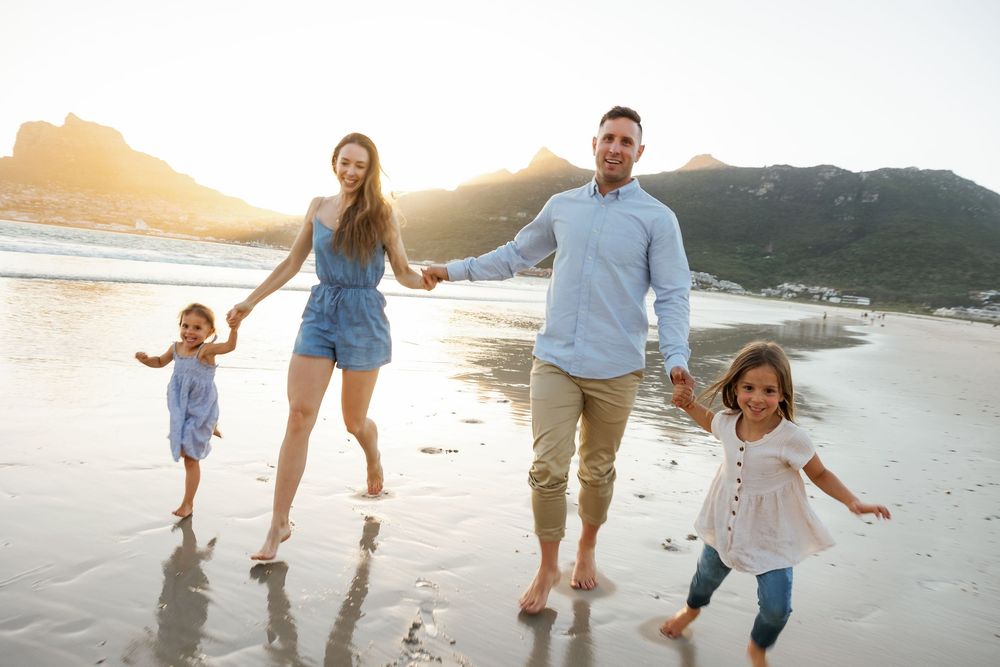 A happy family walking and playing together on a sandy beach at sunset, creating joyful memories by the ocean.