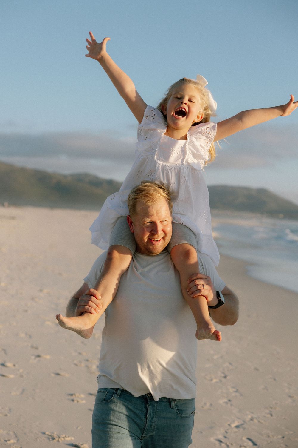 A joyful sequence of playful moments captured on a sunny beach with people in white shirts against a blue sky.