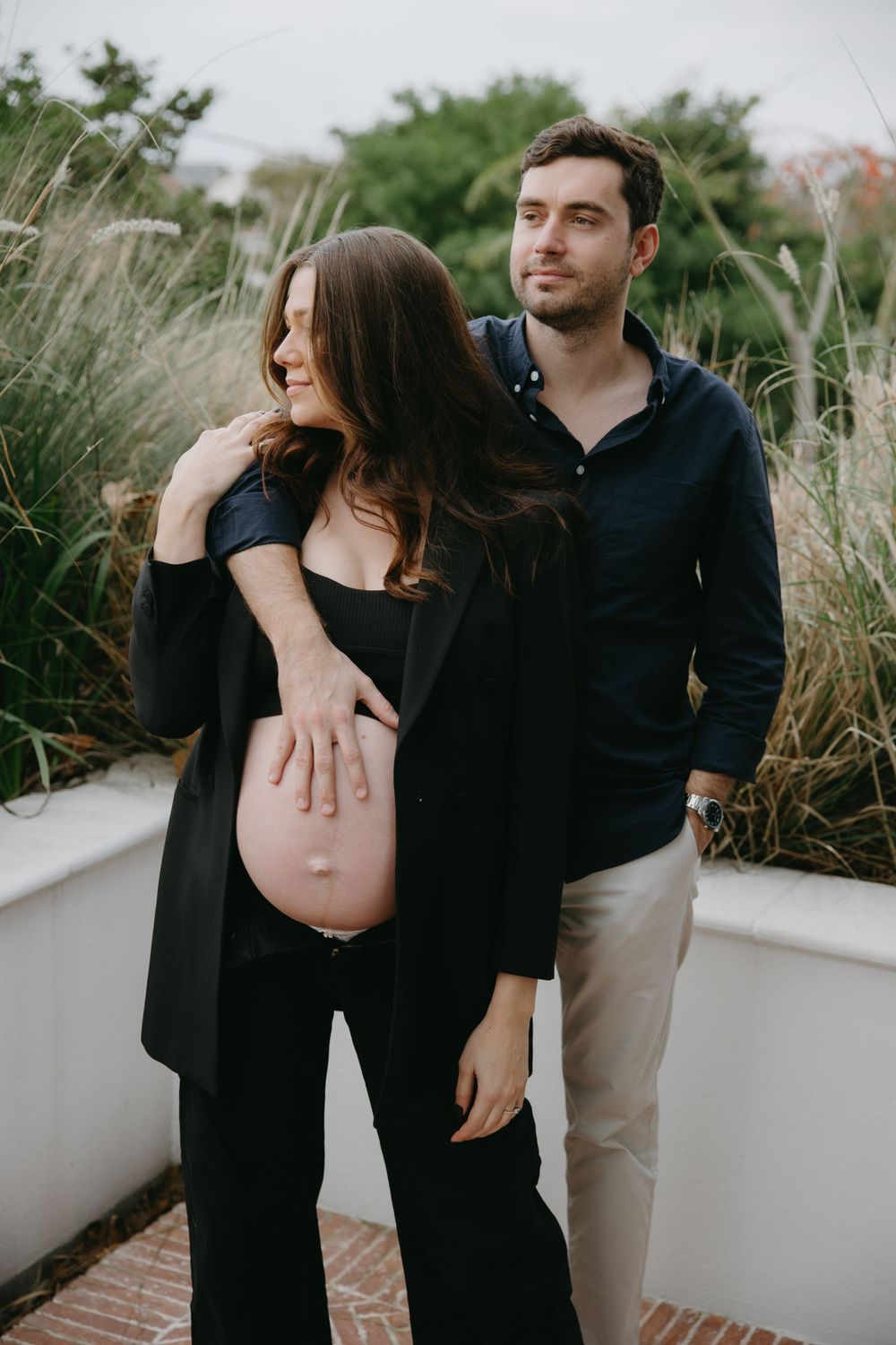 Romantic outdoor maternity photo of couple by tall grasses.
