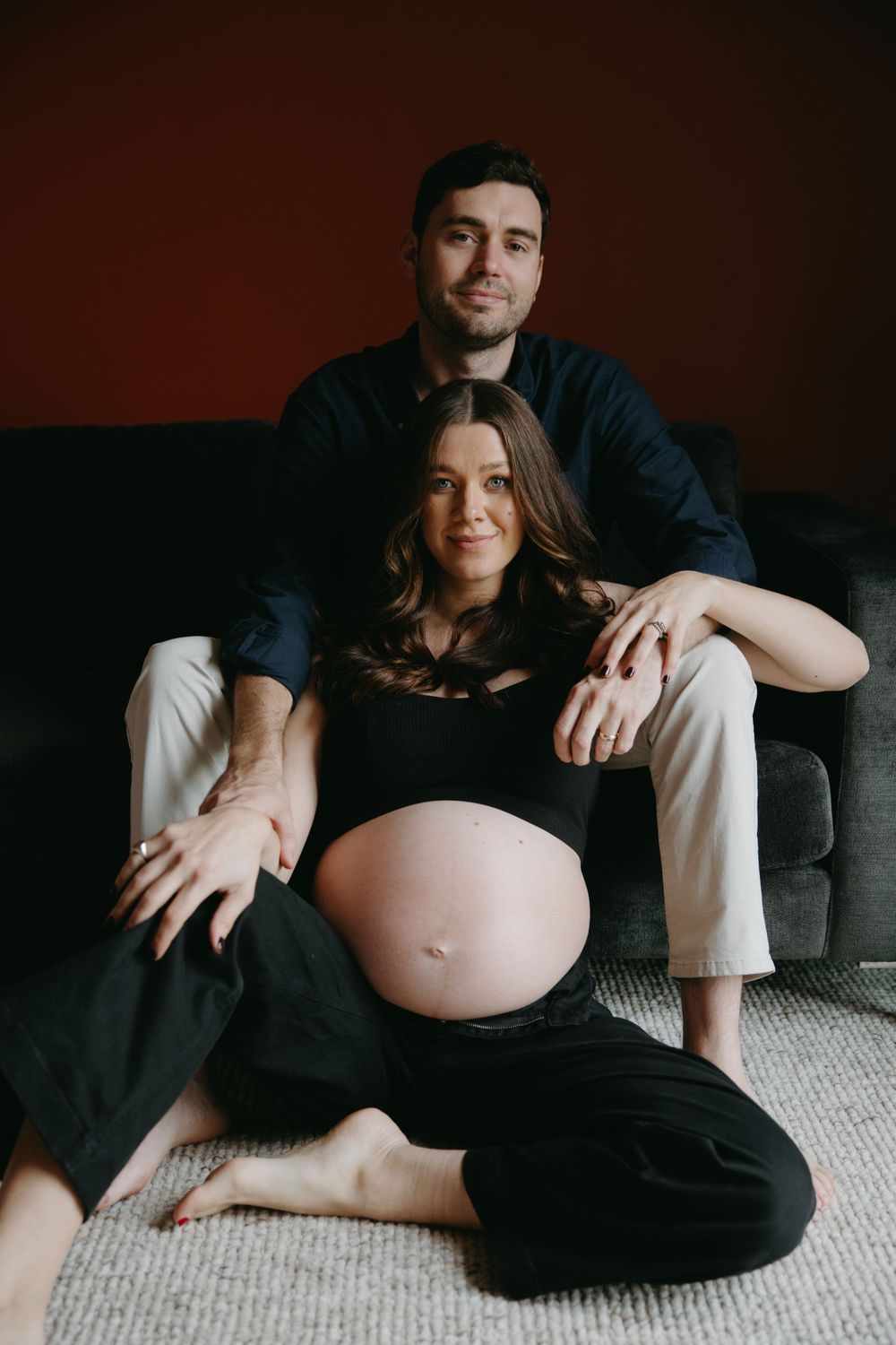 Intimate indoor maternity portrait of couple relaxing on floor.