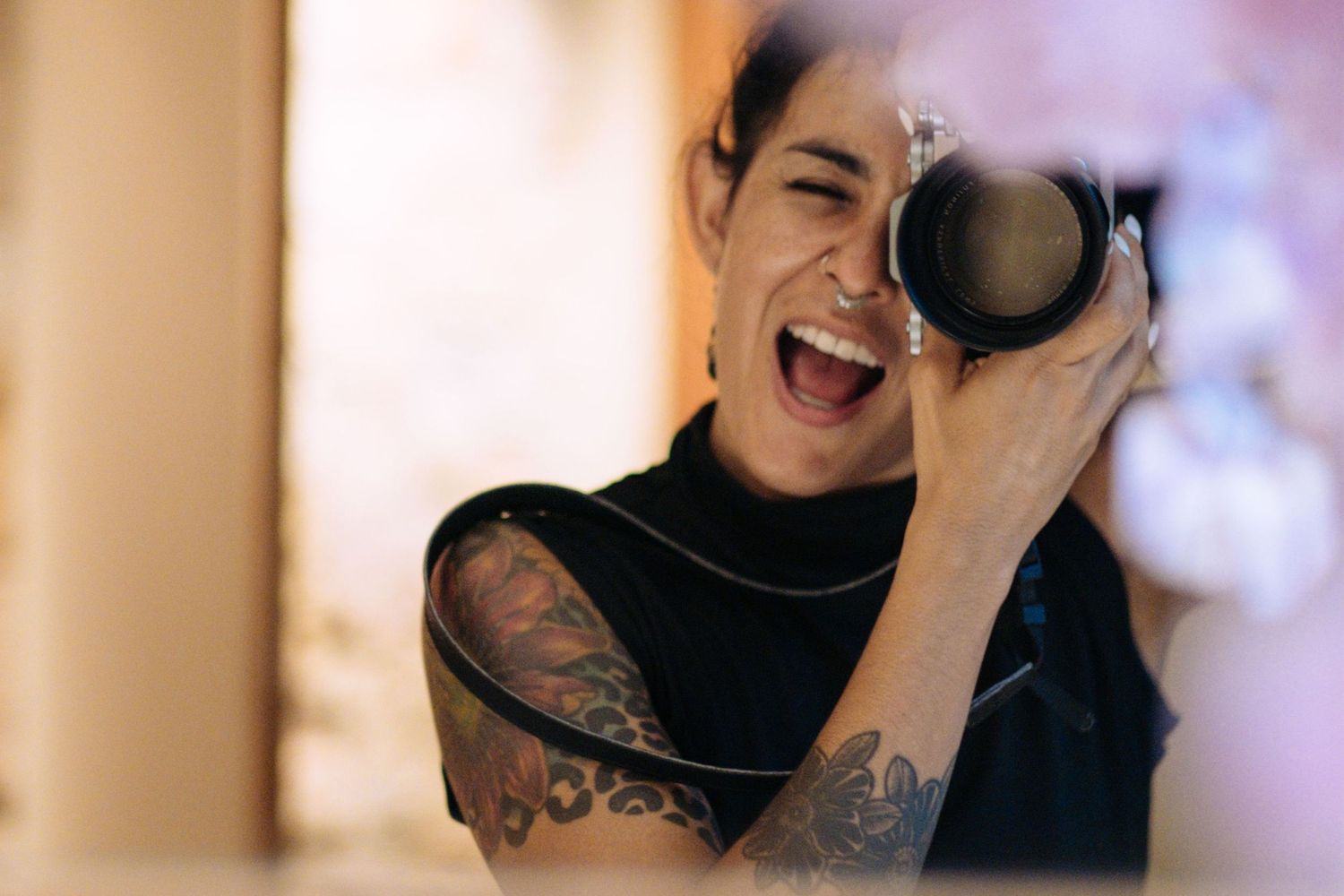 Professional photographer laughing while holding camera in creative portrait shot.