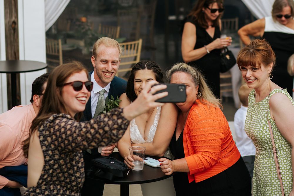 Outdoor wedding guests taking photos and enjoying the celebration in summer attire.