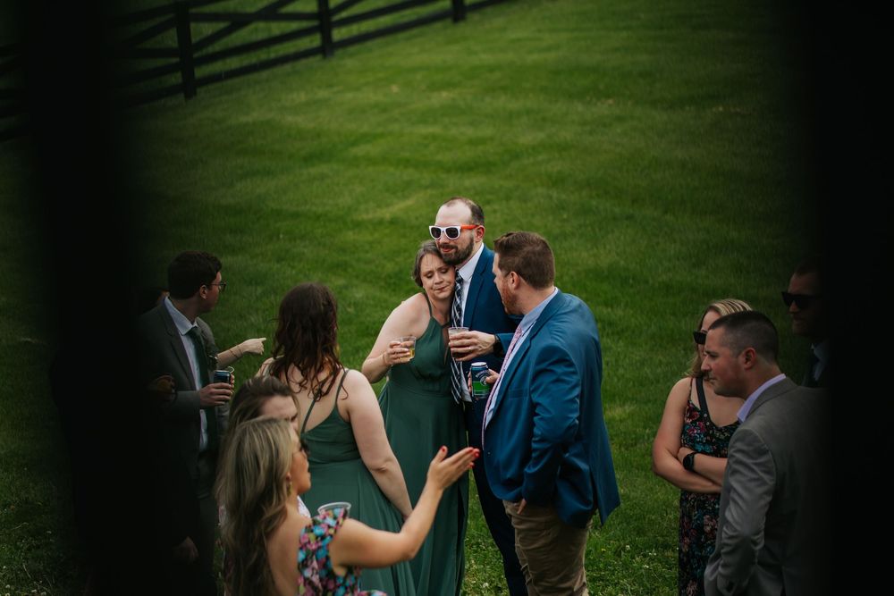 Wedding guests socializing on a green lawn during an outdoor reception event.