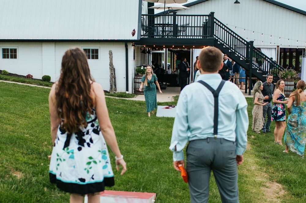 Outdoor wedding venue with white barn building and grassy lawn area for games and activities.