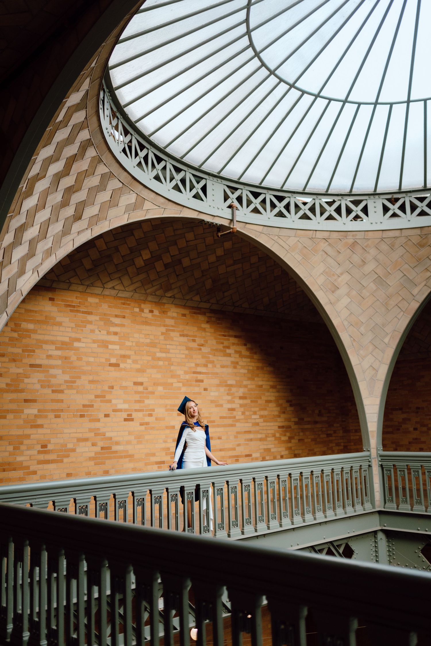 UC Berkeley graduate poses inside Hearst Memorial Mining Building. The beautiful architecture and dome ceiling are highlighted.