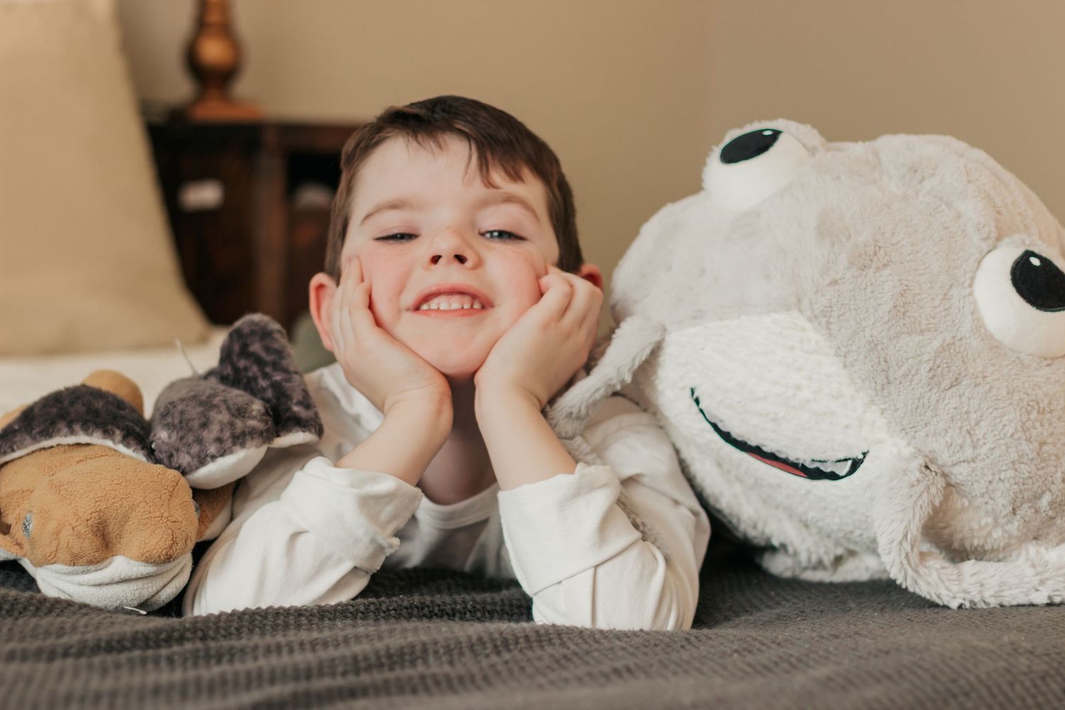 A child lies on a couch with stuffed animals including a large white plush toy with a friendly smile | Annual Birthday Photos for Kids