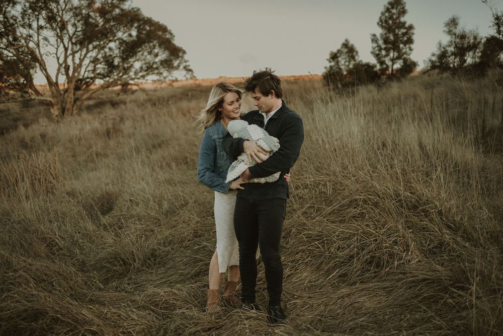A couple shares an intimate moment together in a golden field during sunset.
