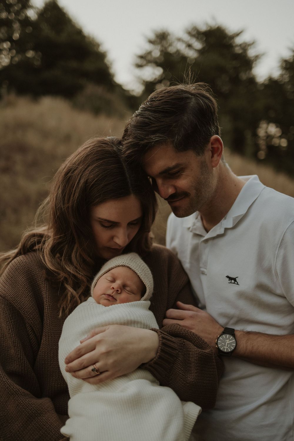 A series of intimate family photos showing parents tenderly holding and bonding with their newborn baby in warm sepia tones.