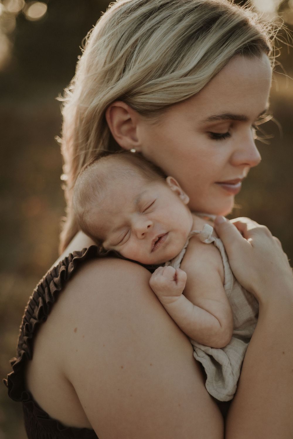 A tender moment captured in warm lighting shows a parent gently cradling and embracing their newborn baby.
